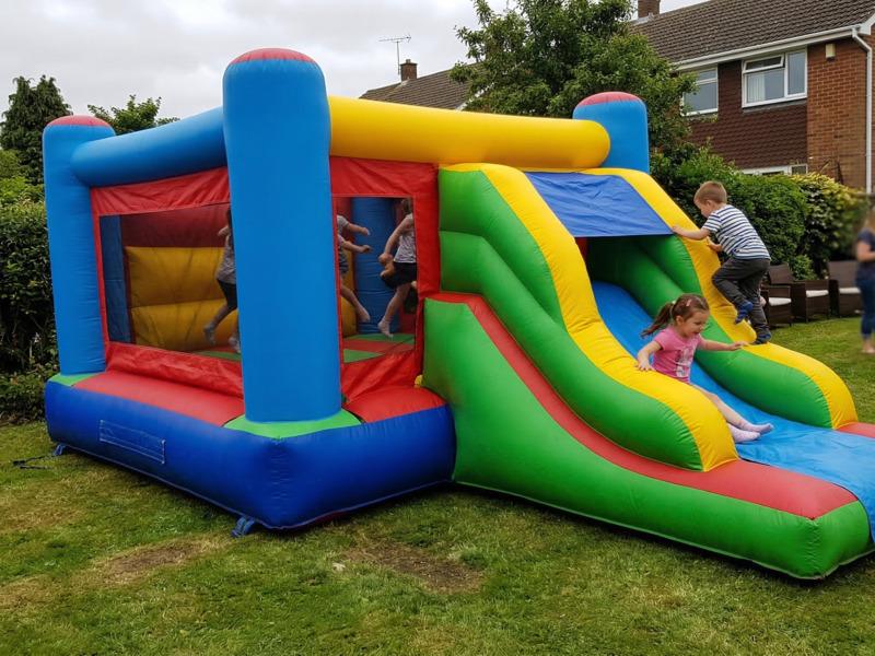 A combo bouncy castle with built-in slide set up on a lawn for a children's party