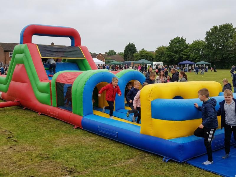 An inflatable obstacle course set up at a school fete with children queuing to take part
