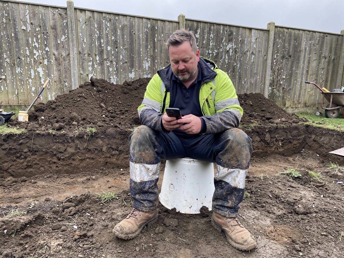 Landscaper checking his business website on his phone during a break on site